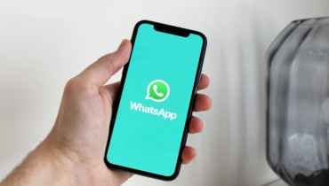 Mehe käsi hoiab telefoni, mille ekraanil on kirjas WhatsApp