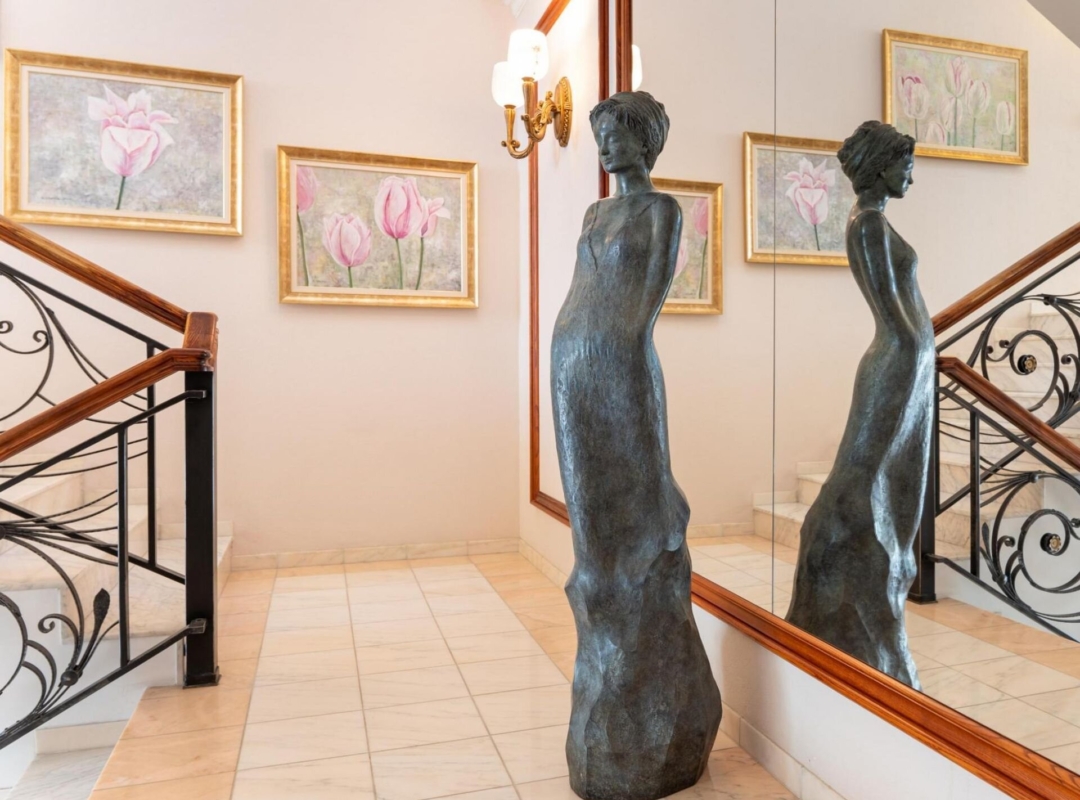 Elite clinics staircase with a sculpture of a woman in the foreground and paintings in the background.
